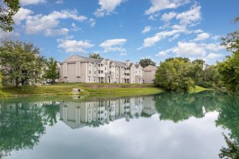A large building is reflected in the still water of a lake.